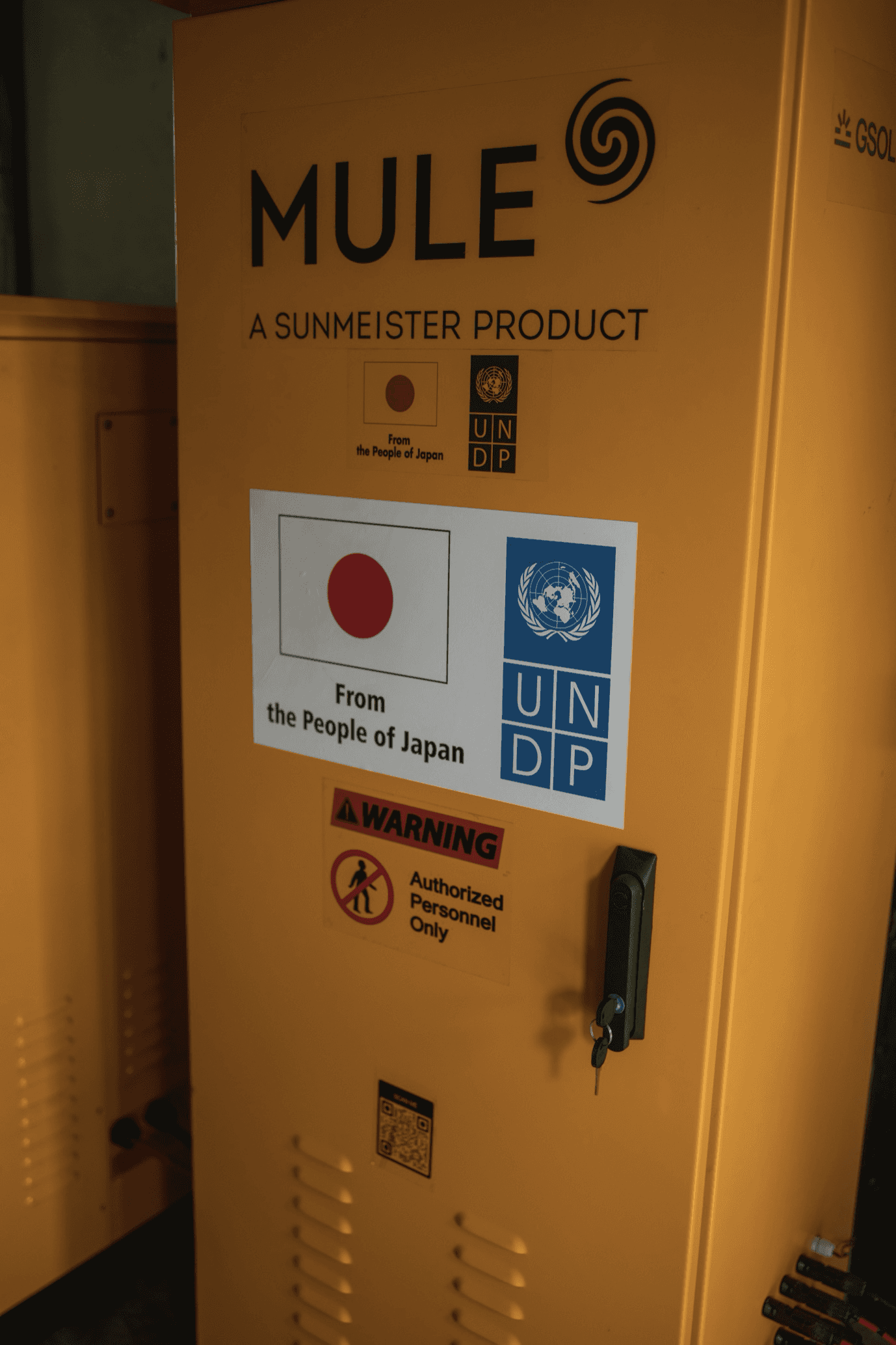 The MULE plug-and-play hybrid solar system, branded by Sunmeister, with the UNDP logo and the flag of Japan