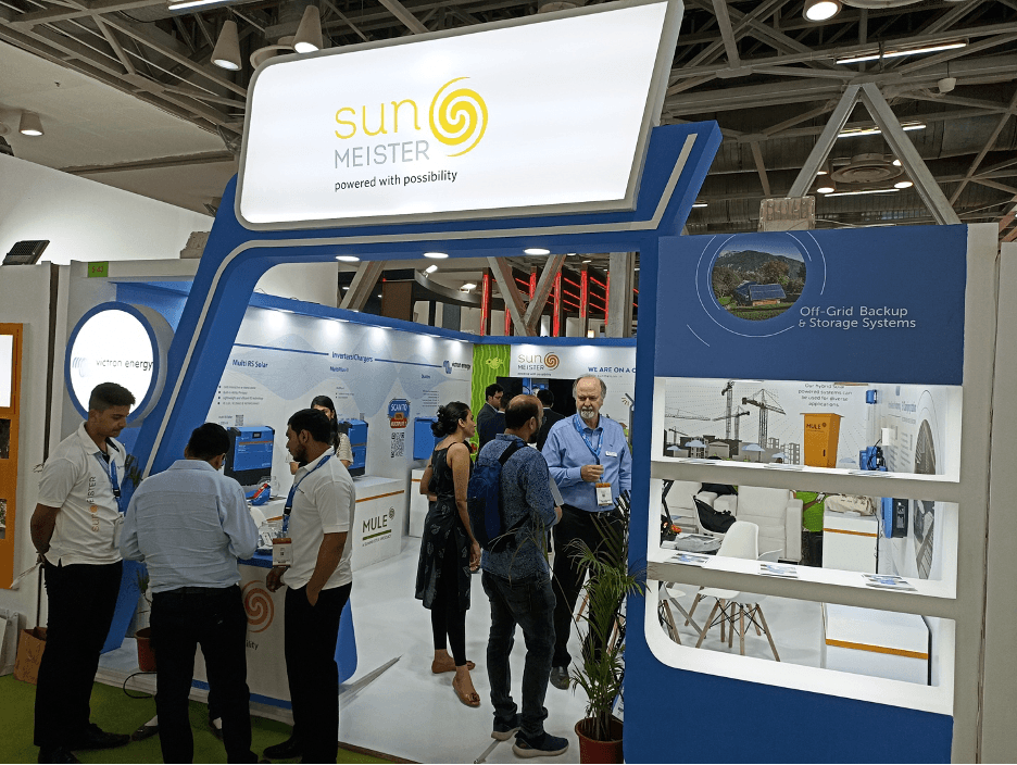 Sunmeister Energy at REI 2023: Showcasing Victron Energy Products and The Mule – a decentralised renewable energy technology 1 Sunmeister stall at Renewable Energy India Expo, with staff presenting Sunmeister's MULE,  an off-grid/hybrid solar installation to customers